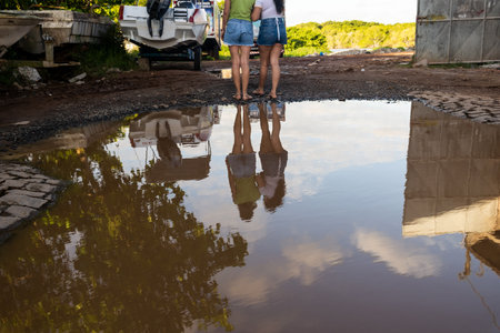 Two women reflected in the puddle of water, embracing. City of Valenca, Bahia.の写真素材
