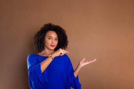 Beautiful young business woman making hand gestures. Standing against a brown background. studio portrait.の写真素材