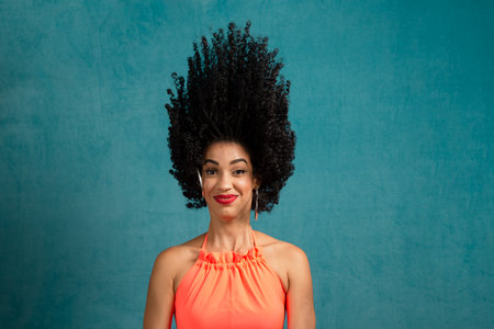 Beautiful young woman making movements with her head and hair. Isolated blue background.