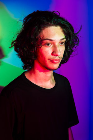 Portrait of young handsome man with colorful shadows on photographic background. rgb colors