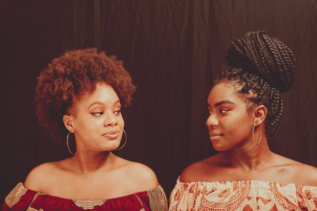 Close-up portrait of two female friends together. Isolated on dark background.の写真素材