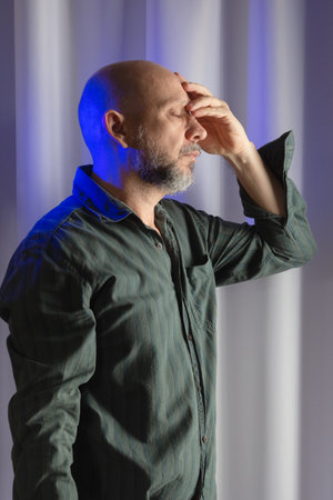 Man standing, worried and thoughtful. studio portrait. white curtain backgroundの写真素材