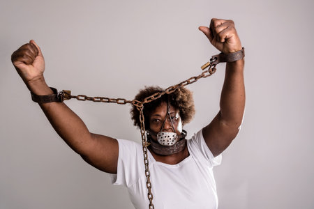 Portrait of a woman trapped with old rusty chains and mask on her face. Slave trade prevention concept.の写真素材