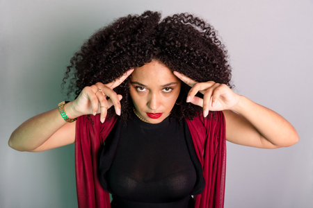 Beautiful young woman touching her hair with a red cloth. studio portraitの写真素材