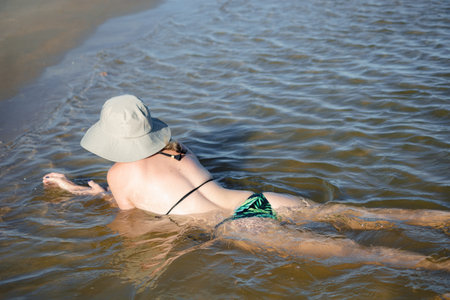 Woman with her back bathing in the sea on a sunny day. Taquari, Guaibim beach, Valenca, Bahia.の写真素材