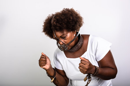 Portrait of a black woman with chains around her body and an iron mask over her mouth. Slavery in...