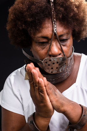 Portrait of the face of a black woman with an iron mask on her face, representing the slave Anastacia. Praying for less pain. Slavery in Brazil.の写真素材