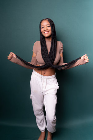 Portrait of beautiful young woman, standing, with big braids in her hair. Isolated on dark green backgroundの写真素材