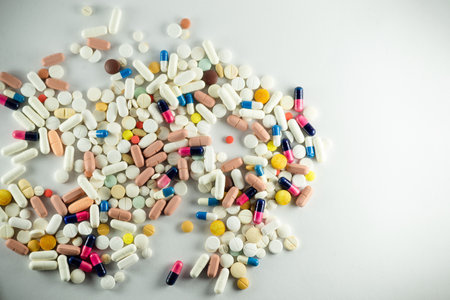 Several pills of different colors laid out on a light gray surface. Medical supplies.