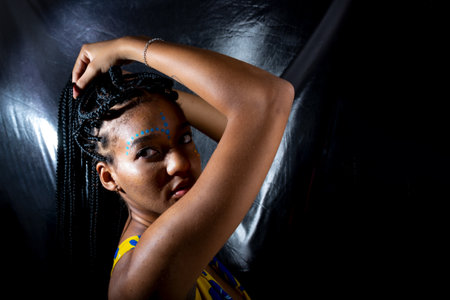 Portrait of a beautiful black woman with long braids in her hair and face paint. Isolated on silver background.の写真素材