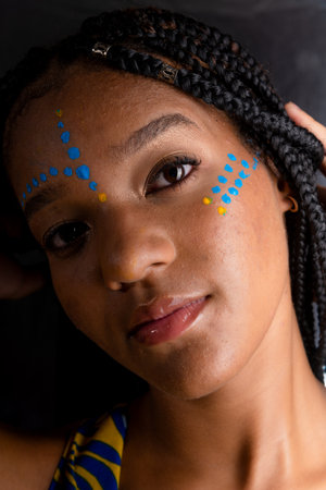Close-up portrait of a beautiful black woman with colorful paint on her face. Isolated on silver background.の写真素材