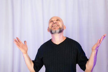 Bearded and bald man making various signs with his hands. Isolated on gray color background.の写真素材