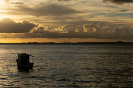 Silhouette of a boat against the dramatic sunset under the sea. Salvador, Brazil.