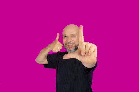 Bearded and bald man making various signs with his hands. Isolated on pink background.