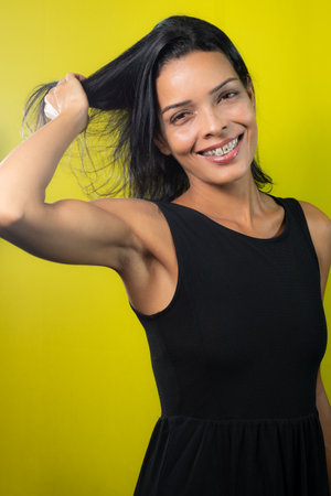 Studio portrait of beautiful model, smiling and looking at camera. Isolated on yellow background.の写真素材