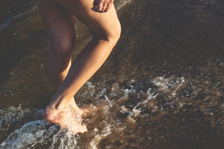 Part of a woman's legs walking in the water at the beach. Guaibim, Valenca, Bahia.の写真素材