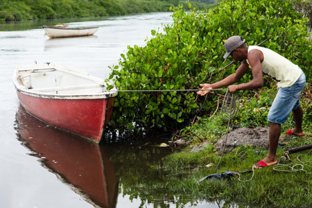Aratuipe, Bahia, Brazil - August 31, 2018: Fisherman pulling the canoe to the riverside. City of Aratuipe, Bahia.のeditorial素材
