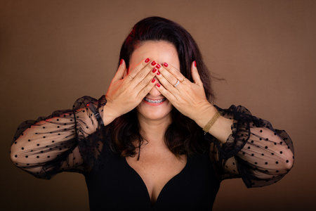 Woman coaching, hands in front of face. Shame, fear concept. Motivational and democratic management. Isolated on brown background.の写真素材