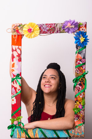 Beautiful woman behind a frame adorned with flowers and colorful cloths in an upright position....