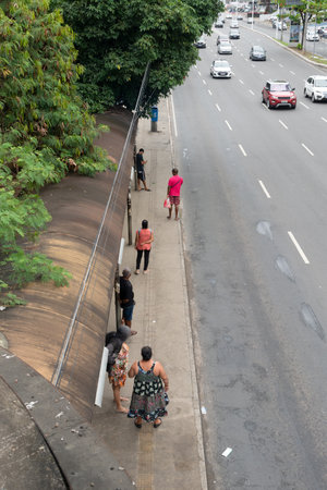 Salvador, Bahia, Brazil - August 11, 2023: Passengers standing waiting for transport at a bus stop on Avenida Tancredo Neves in Salvador, Bahia,のeditorial素材