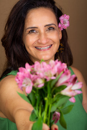 Woman, Caucasian, very happy and in love holding bouquet of flowers. Isolated on brown background.の写真素材
