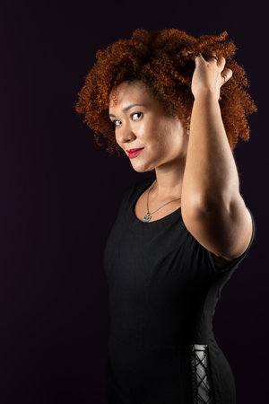 Beautiful attractive woman with red hair, smiling and happy, posing for the photo in black clothes against lilac background.の写真素材