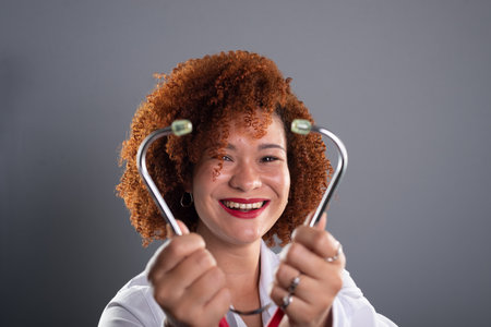 Portrait of a female veterinarian with red hair, wearing a white uniform and holding a stethoscope close to her face. animal care. Isolated on gray background.の写真素材