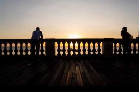 Salvador, Bahia, Brazil - August 25, 2023: Silhouette of tourists enjoying the sunset from the balustrade of Porto da Barra in the city of Salvador, Bahia.のeditorial素材