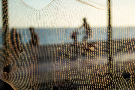 Silhouette of cyclists and people walking on the edge of a beach against sunset. Practice of...