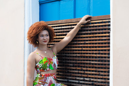 A beautiful woman with red hair, in colorful dress, holding on to a brown wooden railing. Happy person traveling.の写真素材
