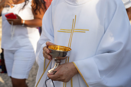 Salvador, Bahia, Brazil - January 07, 2022: Hands of a Catholic priest holding the hostia cup during open mass at the Senhor do Bondim church in the city of Salvador, Bahia.のeditorial素材