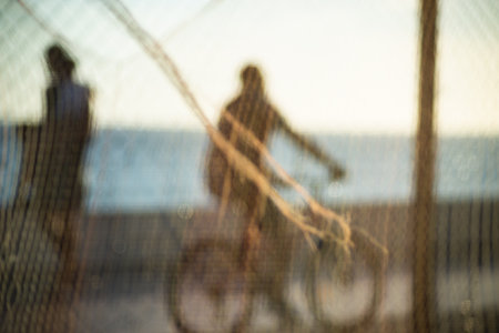 Silhouette of cyclists and people walking on the edge of a beach against sunset. Practice of physical exercises and relaxation of the mind.の写真素材