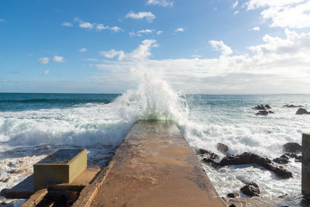 Sea wave crashing hard on a beach pier. Wild nature.の写真素材