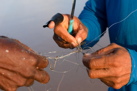 Salvador, Bahia, Brazil - April 26, 2019: Hands of fishermen untying fishing line. Pole fishing.の写真素材