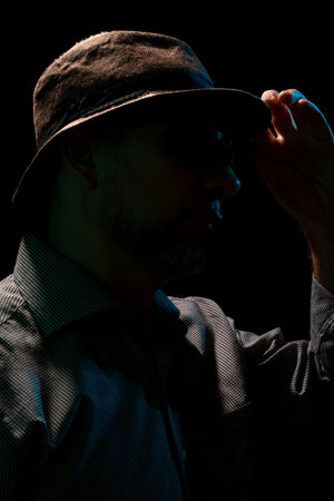 Mysterious man wearing hat and sunglasses. Portrait in dark studio.の写真素材