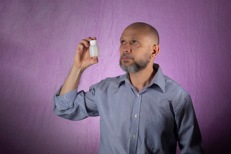 Man holding white color packaging of medicine against pink background.の写真素材