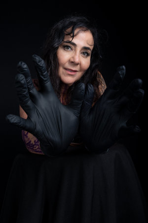 Close-up of beautiful tattoo artist wearing black gloves against black backgroundの写真素材
