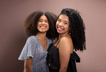 Portrait of two young women friends together. Isolated on salmon-colored background.の写真素材