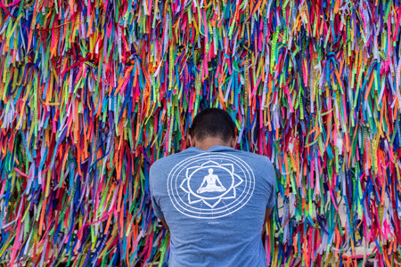 Salvador, Bahia, Brazil - August 12, 2022: Catholic prays in front of the Senhor do Bonfim souvenir ribbons in the Senhor do Bonfim Church in the city of Salvador, Bahia.のeditorial素材