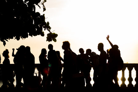 People are seen, in silhouette, walking along the shore of Porto da Barra beach in the city of Salvador, Bahia.の写真素材