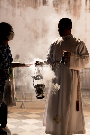 Salvador, Bahia, Brazil - December 13, 2023: Catholic seminarian waving the candlestick during mass at the church of Santa Luzia in the city of Salvador, Bahia.のeditorial素材