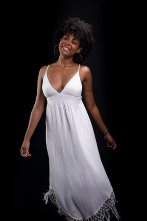 Beautiful beauty, with black power hair, standing moving her white dress against a black background.の写真素材