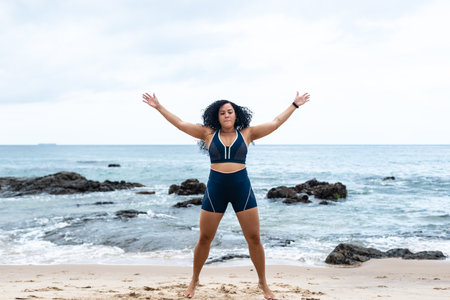 Fitness woman, athlete, doing jumping jacks on the beach sand. Healthy lifestyle.の写真素材