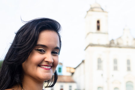 Portrait of beautiful woman, with long black hair, outdoors posing for photo. Happy person traveling.の写真素材