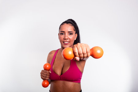 Beautiful woman, dressed in gym clothes, holding dumbbells towards the camera. Healthy life with physical exercise.の写真素材