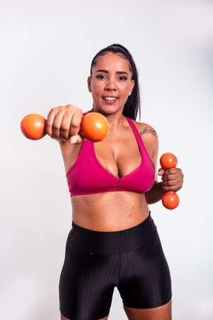 Beautiful woman, dressed in gym clothes, holding dumbbells towards the camera. Healthy life with physical exercise.の写真素材