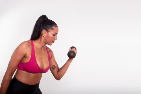 Young fitness athlete woman, dressed in gym clothes, doing arm exercise with dumbbells. Healthy life...