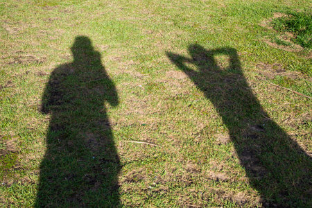 Shadows of two unidentified people on the grass floor. Man and womanの写真素材