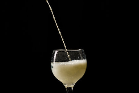 Milk falling into a glass cup. Isolated on black background.の写真素材