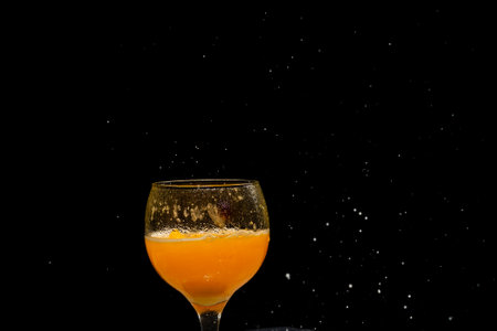A glass goblet with orange juice inside. Isolated on black background.の写真素材